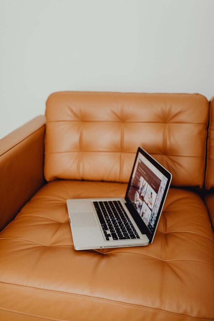 pexels-photo-5882556-5882556 A sleek laptop rests on a luxurious tan leather couch, embodying a modern lifestyle.